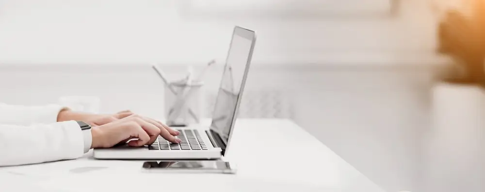 Close up of woman using laptop writing a blog